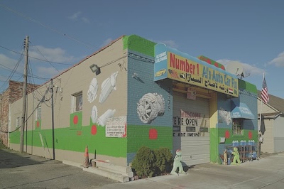 A shop called Number 1 Al&rsquo;s Auto Care Fix (english and arabic) is painted outside with pictures of different car parts