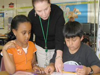 A teacher helping her students with a reading assigment. NHEC