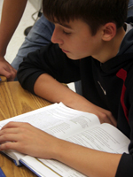 A student completing a reading assignment from his text-book. NHEC