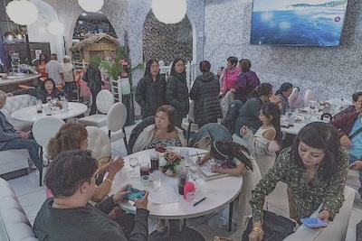 A family gathers around tables at a Filipino restaurant to celebrate a baptism. 