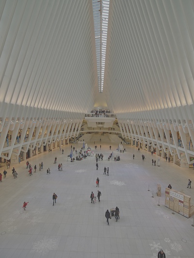 Walls extend upwards and meet to make a pointed ceiling. Light filters through the skylights. The ceilings are very high and the whole building is white.