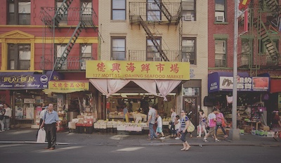 A small crowd of people walk in front of a store front titled Dahing Seafood Market. 