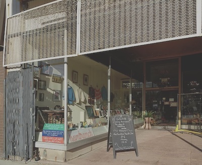 Store front with chalkboard in front of the store reading "A Collectible Clothing Boutique. A Place for Something Unique."