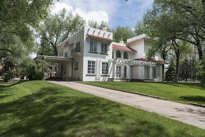 White house with two stories a red clay tile roof.