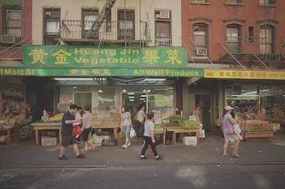 Pedestrians walk in front of Huan Jin Vegetable store front in China Town