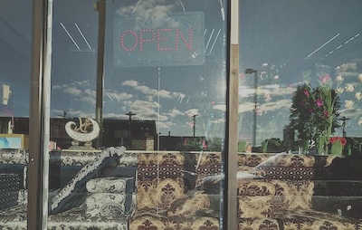 A store window containing pillows and chairs with ornate fabric designs.