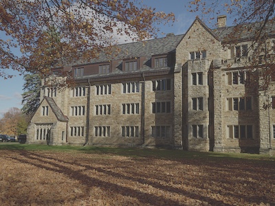 Beige four story stone building with a black roof. 