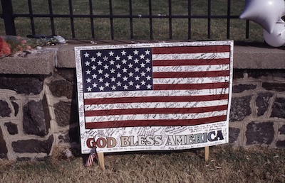 Sign of an American flag reading God Bless America covered in signatures