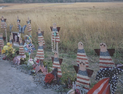 Handmade wooden angels painted with the American flag design. Each is labeled with the name of a passenger from flight 93 who did not survive. Some of the angels are accompanied with photos or sentimental items.