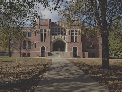 Walkway leading the the theater building which has stairs going up to the door and classic brick architecture.