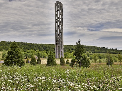 Grey obelisk in a field with trees 