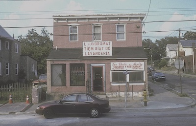 Photo taken in 2006 of the same brick building as above on Saunders Street in Camden, New Jersey. Two signs on the outside of the building written in Vietnamese indicating where to enter for the mexican restaurant and for laundry service