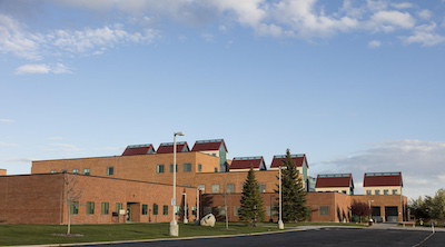 Brown brick buildings with red metal roofs and sky lights.