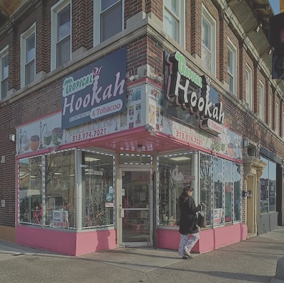 A corner store with two large signs reading Tropical Hookah facing each steet above the door.