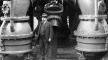 Photo, Man standing below generator unit, unidentified powerhouse, n.d., University of Washington Photo, Man standing below generator unit. . . , n.d., University of Washington